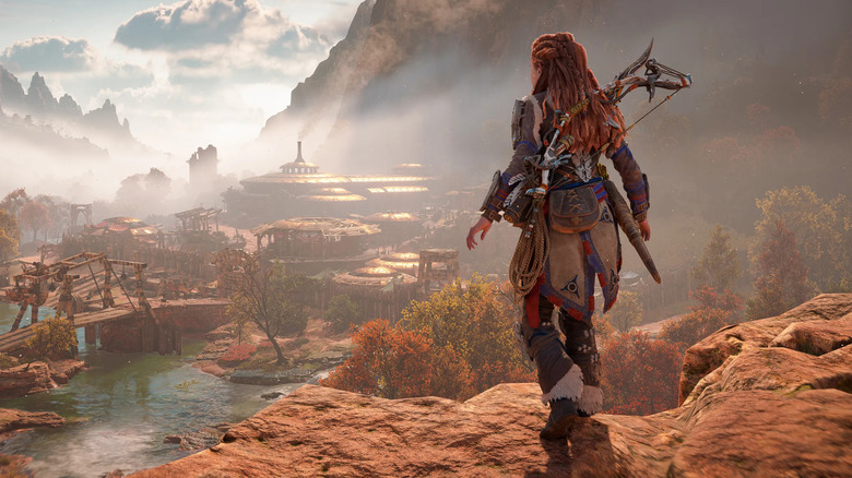 Aloy surveys a city by a river in Horizon Forbidden West