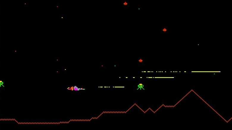A spaceship blasts a green alien ship in Defender
