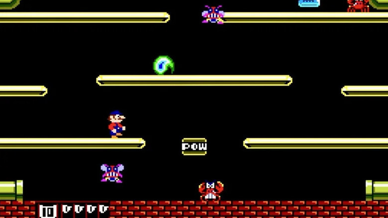 Mario stands on a platform overlooking a crab and grimacing fly in Mario Bros.