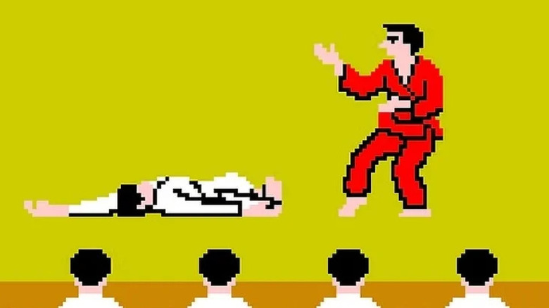 A fighter in a red gi stands over an incapacitated fighter in a white gi in 