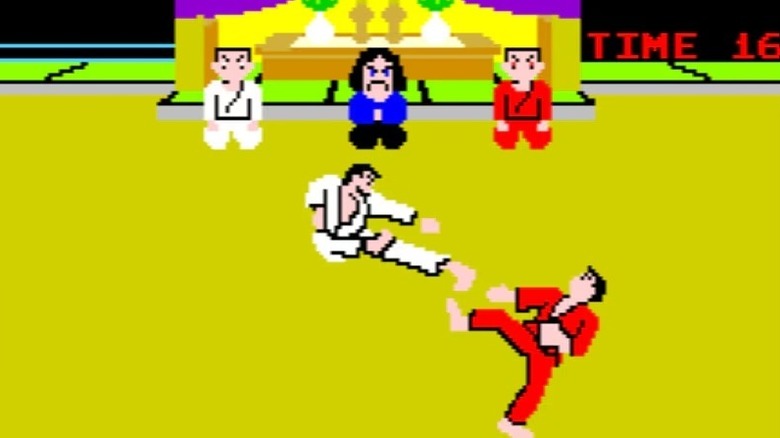 A fighter in a white gi lunges at a fighter in a red gi in "Karate Champ" (1984)