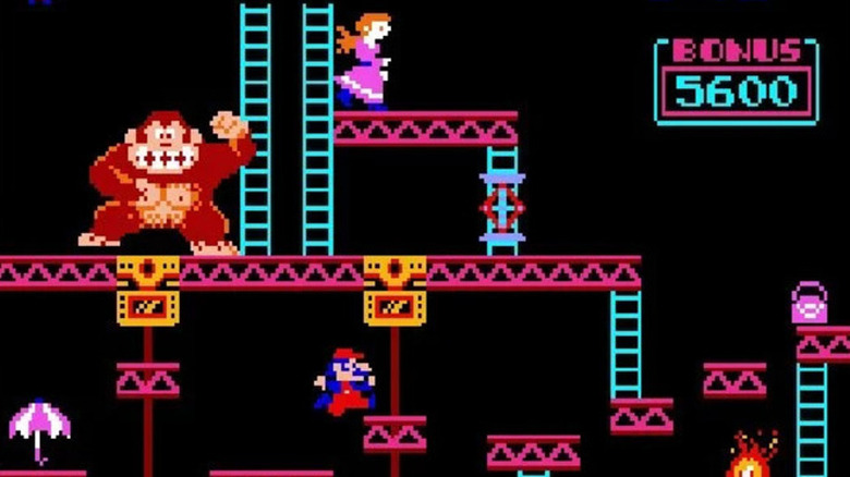 Mario jumps on a moving platform as Donkey Kong beats his chest above him in Donkey Kong