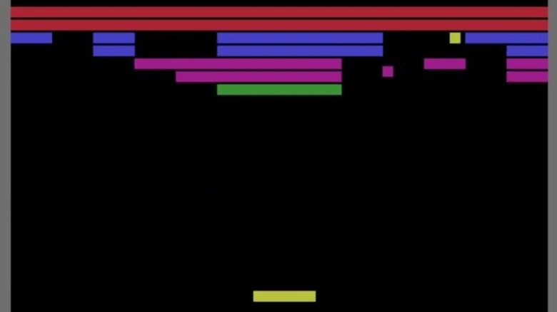 A yellow paddle sends a ball into lines of colored tiles in Breakout