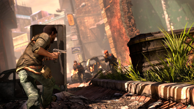 Nathan Drake takes cover from advancing gunmen in a street in Uncharted 2: Among Thieves