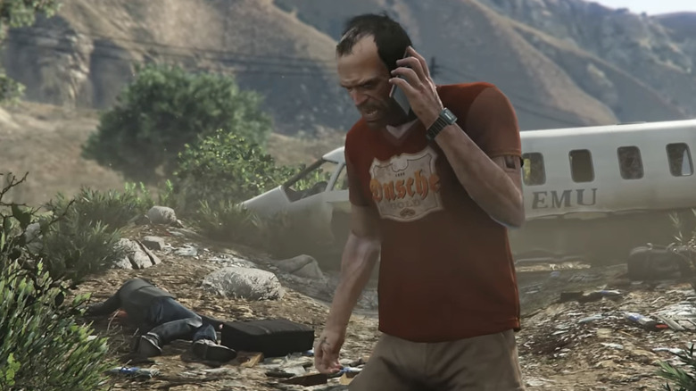 Trevor Phillips talks on a cell phone in front of a downed plane in Grand Theft Auto 5