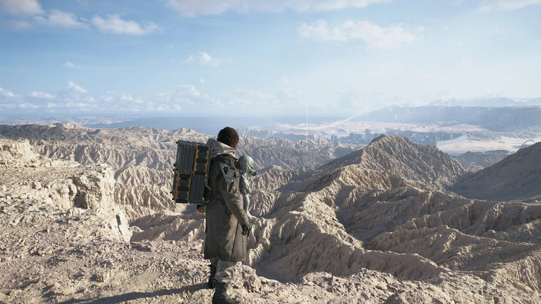 Sam Bridges surveys a mountain range while carrying Lou in Death Stranding 2: On the Beach