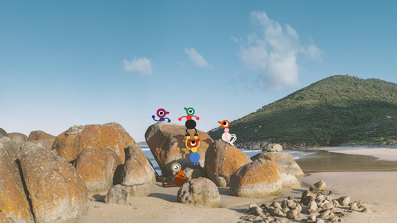 A group of characters climb rocks on a beach together in Big Walk