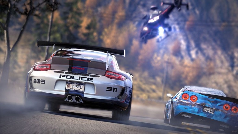 A sports car converted into a police vehicle chases a battered blue sports car as they approach a police helicopter in Need for Speed: Hot Pursuit (2010)