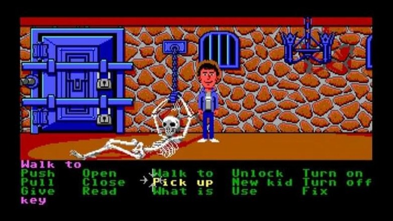 A teenager stands by a chained skeleton in Maniac Mansion