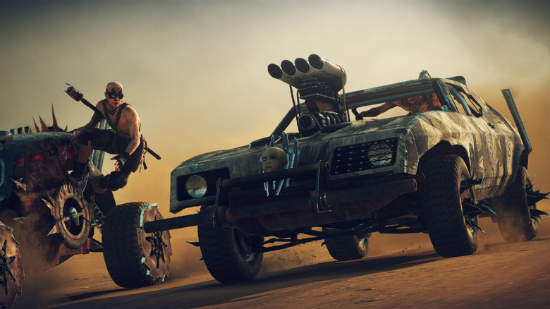 Two cars next to each other racing down a dirt highway in Mad Max