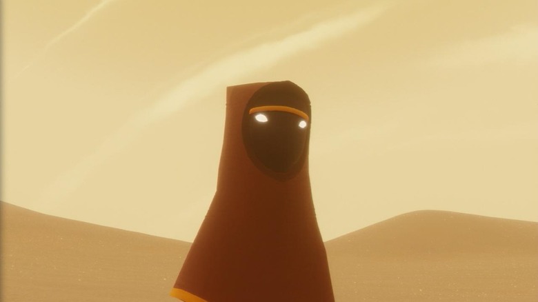 A hooded figure regards the dunes in Journey.