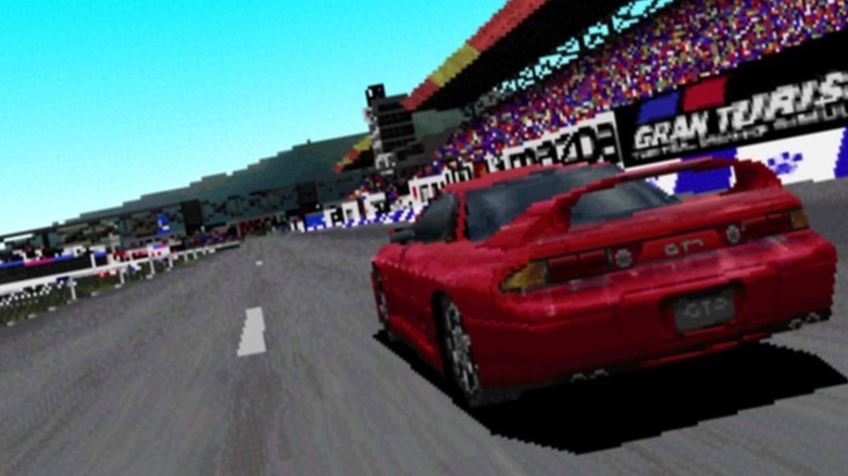 A red car races past packed stands by a track in Gran Turismo 2