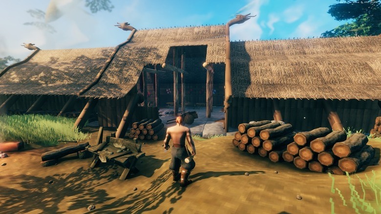 The player character approaches a partially finished building with lumber in Valheim