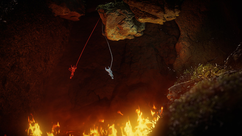The two characters in Unravel Two swinging across a gap of fire