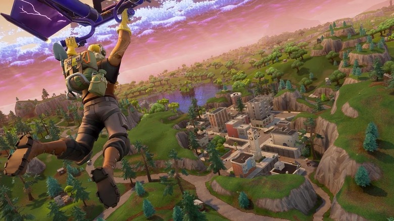 A player rides a hang glider towards a town in a canyon in Fortnite