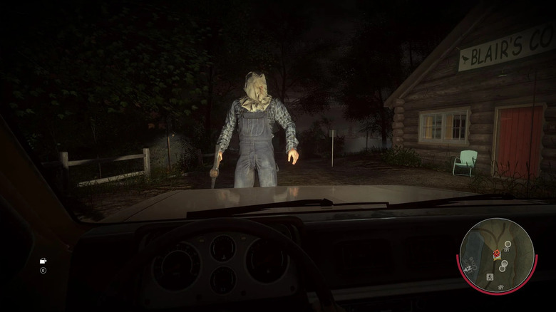Jason Voorhees, wearing a burlap sack on his head, is seen through a car's windshield in Friday the 13th: The Game