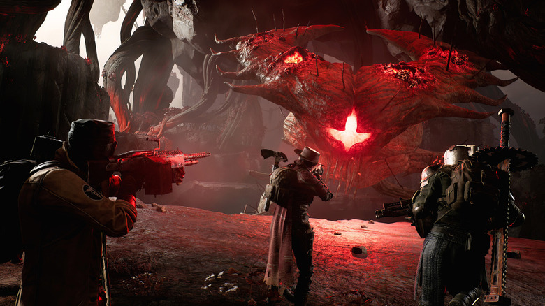 Three player characters shoot at a large monster glowing red in Remnant II