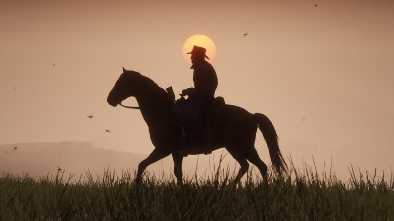 Arthur Morgan rides a horse in front of a sunset in "Red Dead Redemption 2" (2018)