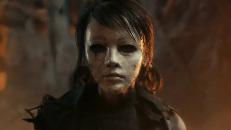A girl stands wearing a cracked porcelain mask in The Medium