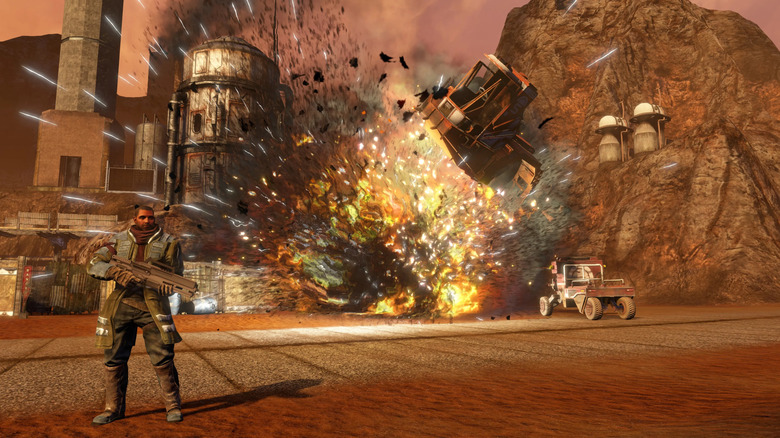 A soldier stands next to an exploding base in Red Faction: Guerrilla