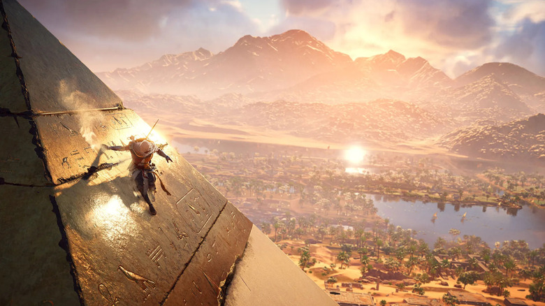 Bayek climbs a pyramid overlooking the Nile River in Assassin's Creed Origins
