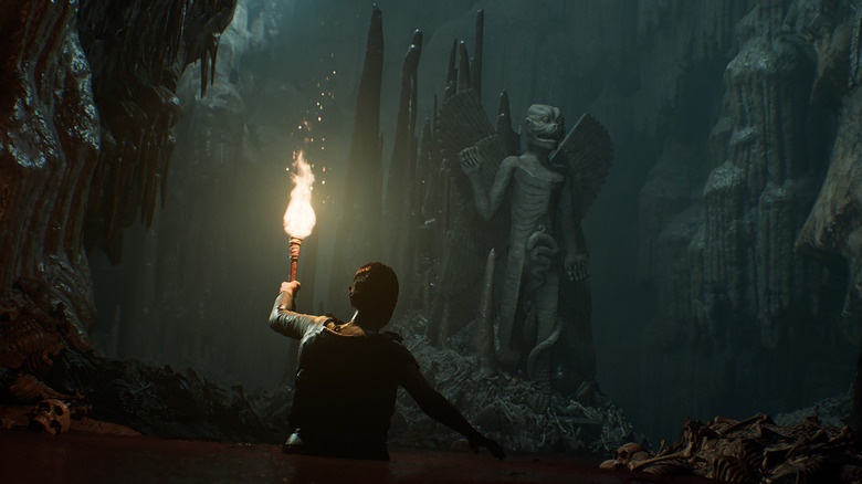 Rachel King wades through water with a lit torch toward a demonic statue in "The Dark Pictures Anthology: House of Ashes" (2019)