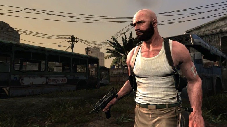 Max Payne walks through a favela holding a submachine gun in Max Payne 3