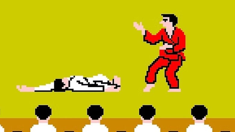 A fighter in a red gi stands over an unconscious fighter in a white gi before an audience in "Karate Champ" (1984)