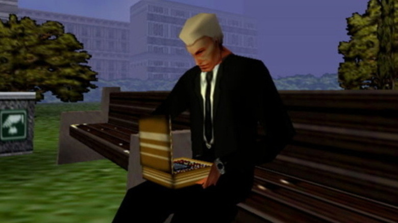 Jim Phelps examines a taped recording on a park bench in Mission: Impossible (1998)