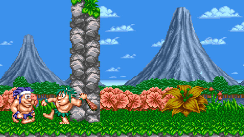 Joe and Mac stand by a stone column in a jungle in Joe & Mac