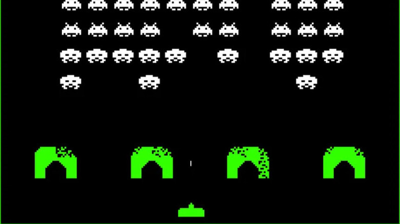 A green ship fires at incoming aliens from behind green barricades in "Space Invaders"