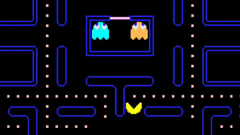 Pac-Man consumes dots as blue and orange ghosts sit in a cell in Pac-Man