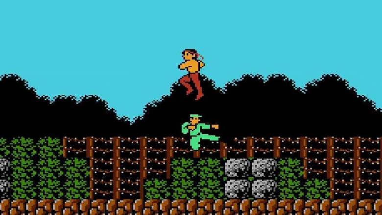 John Rambo jumps over a kicking enemy soldier in Rambo (1987)