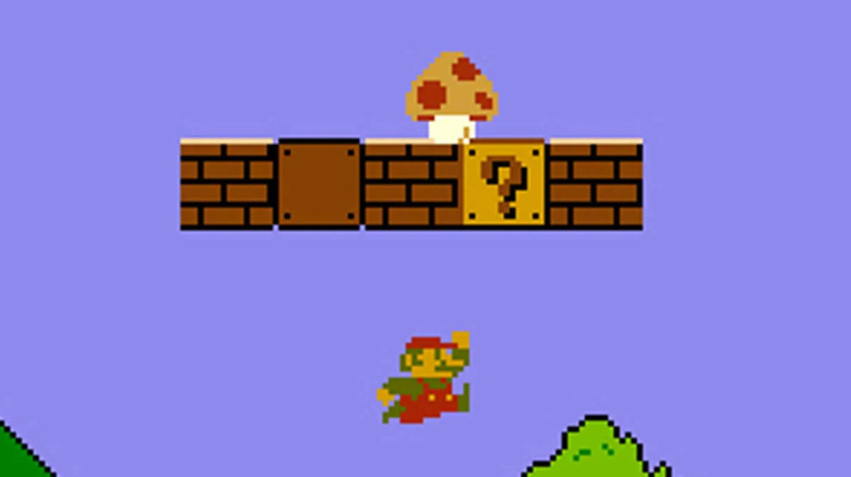 Mario leaps at a question mark block as a mushroom sits above him in Super Mario Bros.