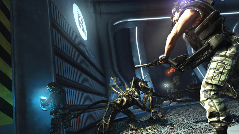 A colonial marine confronts xenomorphs while another marine hacks into a computer in Aliens: Colonial Marines
