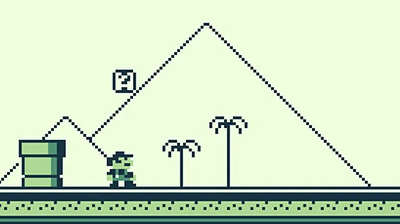 Mario stands by a warp pipe and question mark block with pyramids in the background in "Super Mario Land" (1989)