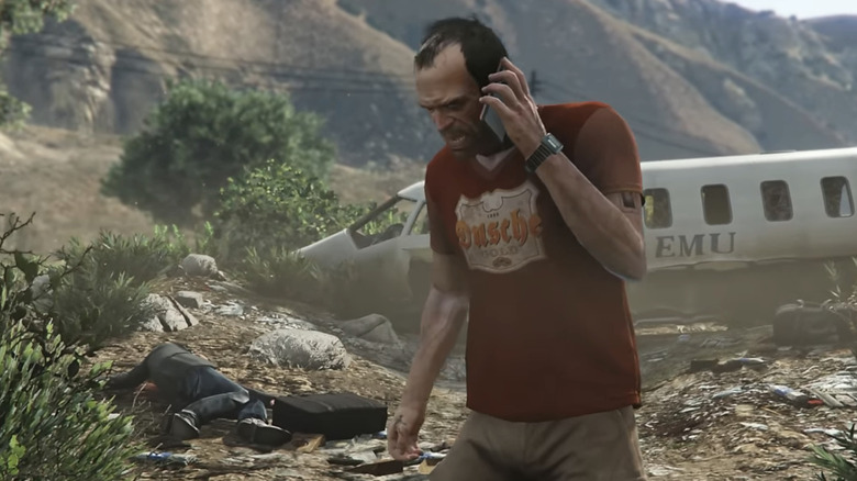 Trevor Phillips talks on a cell phone in front of a downed plane in Grand Theft Auto 5