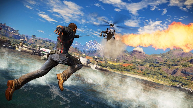 Rico Rodriguez grappling to a helicopter over water in Just Cause 3