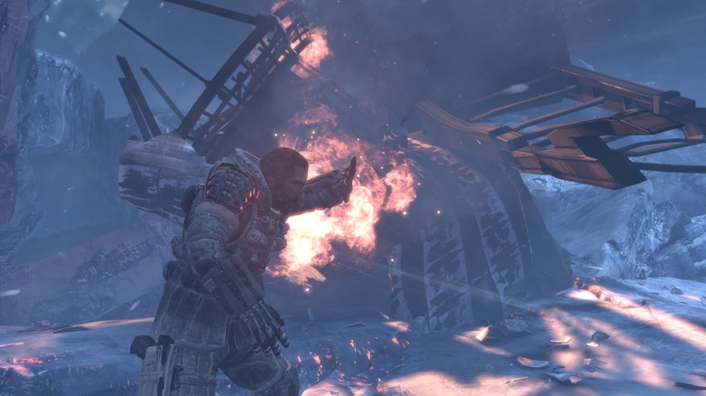 Jim Peyton walks by a burning wreckage while shielding his face in Lost Planet 3