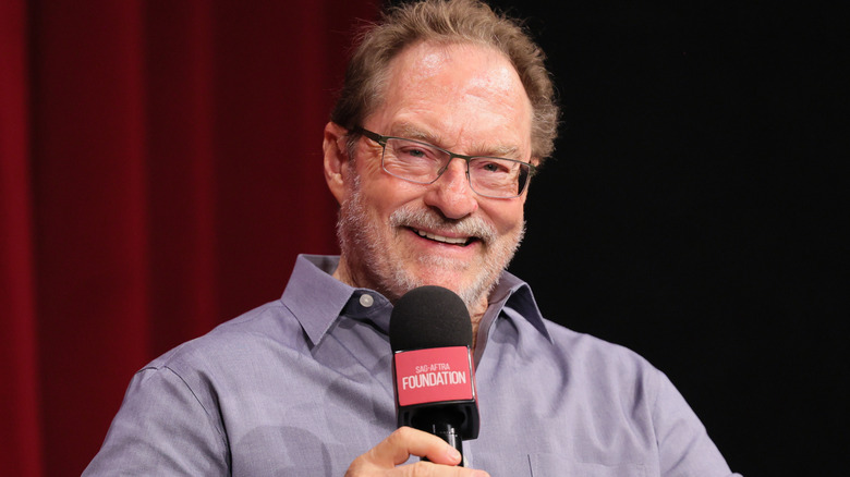 Actor Stephen Root smiling and holding a microphone