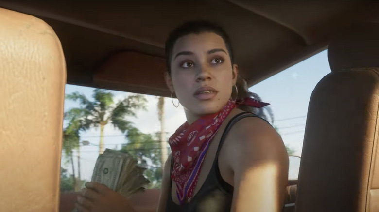 Lucia Caminos looks back in a car while holding a stack of dollar bills in Grand Theft Auto 6