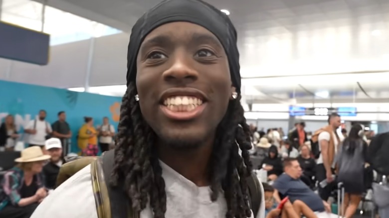 Kai Cenat smiling in front of a crowd of people