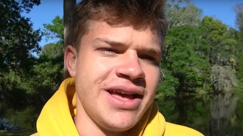 Jynxzi talking into the camera wearing a yellow hoodie outdoors