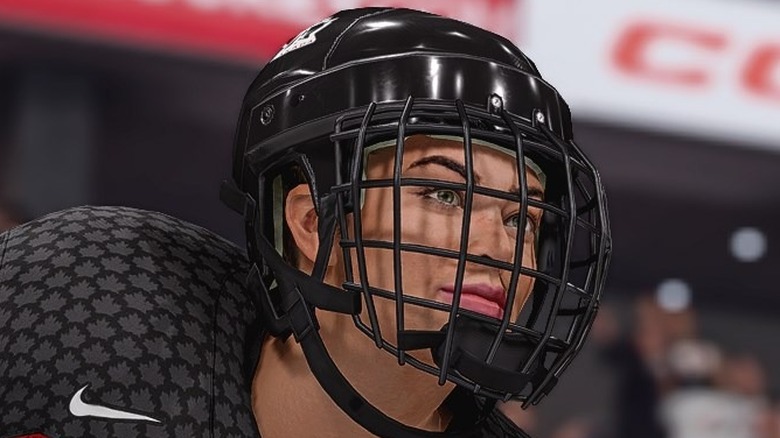 A screenshot from NHL 23, showing a closeup of a player's head. She's smiling, and wearing a black helmet.