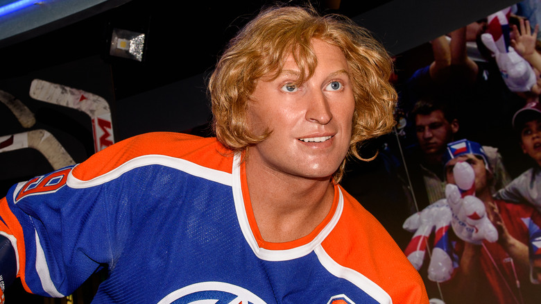 Wayne Gretzky, wearing a blue and orange jersey, smiling.