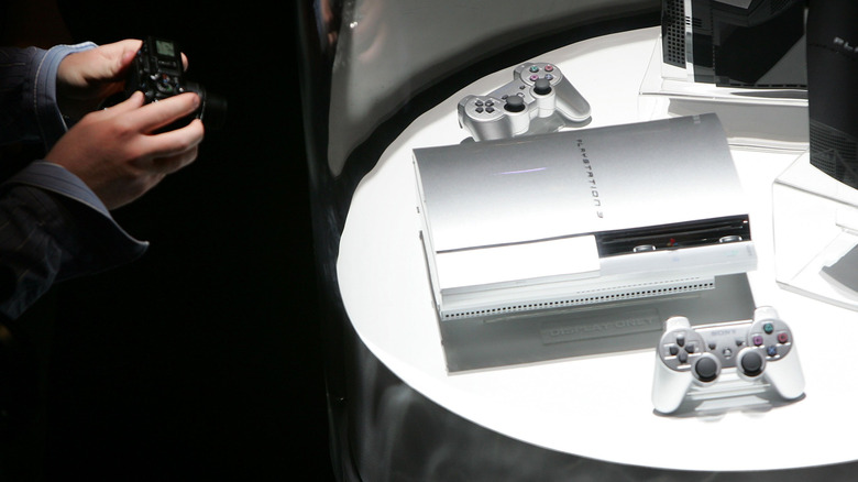 A silver PlayStation 3 console on display with two controllers