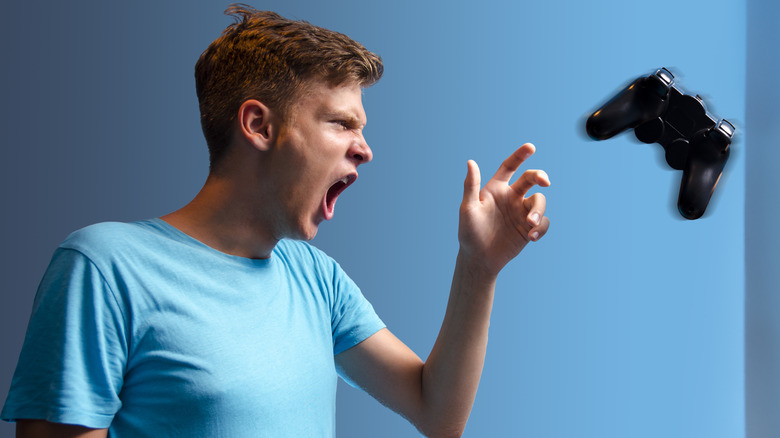 Teenager in blue shirt throwing a PlayStation controller