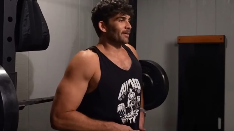 HasanAbi standing by a weight lifting bench