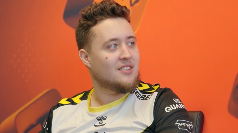 A Vitality team member wearing a jersey with a GGBet logo in front of a GG board