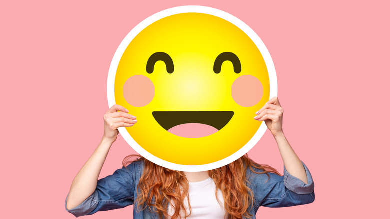 woman holding smiling emoji